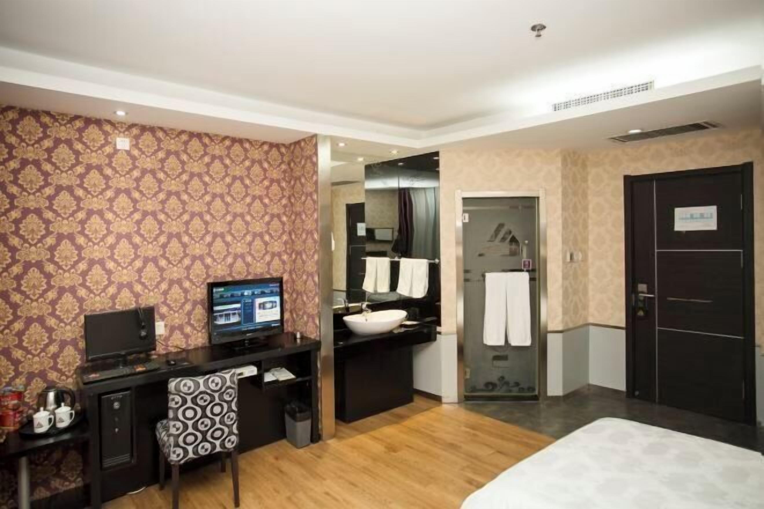 A hotel room with a desk, computer, and a bed.