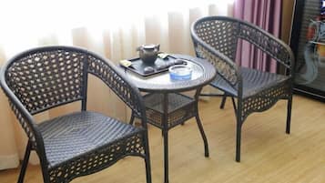A room with two wicker chairs and a small round table, a teapot, and a tray with a teacup and saucer.