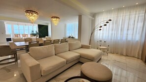 Relax in this stylish living room with a comfortable sofa, ottoman, and dining area.