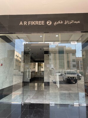 The entrance to a building with a glass door and a sign reading "AR FIKREE 2".