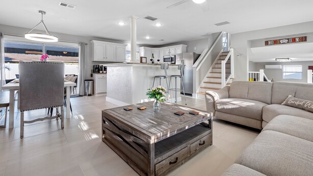 A modern living room with a wooden coffee table, a grey sofa, and a dining area with a white table and chairs. - Luxury Heated Salt Pool House in Perfect Location (Tampa)
