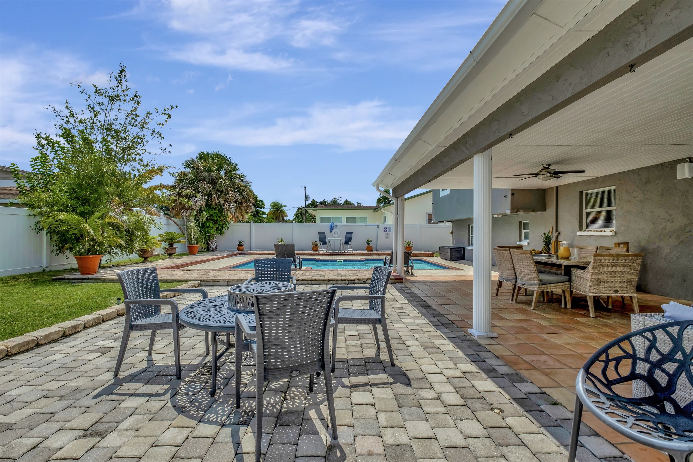 Un patio con piscina, mobiliario exterior y vista a un edificio al fondo.