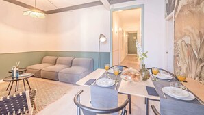 Ein modernes Wohnzimmer mit einer Couch, einem Esstisch, der für das Frühstück gedeckt ist, und einem Flur, der zu einem weiteren Raum führt.