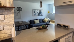 A modern kitchen with a dining area, a stone wall, and a ceiling fan.