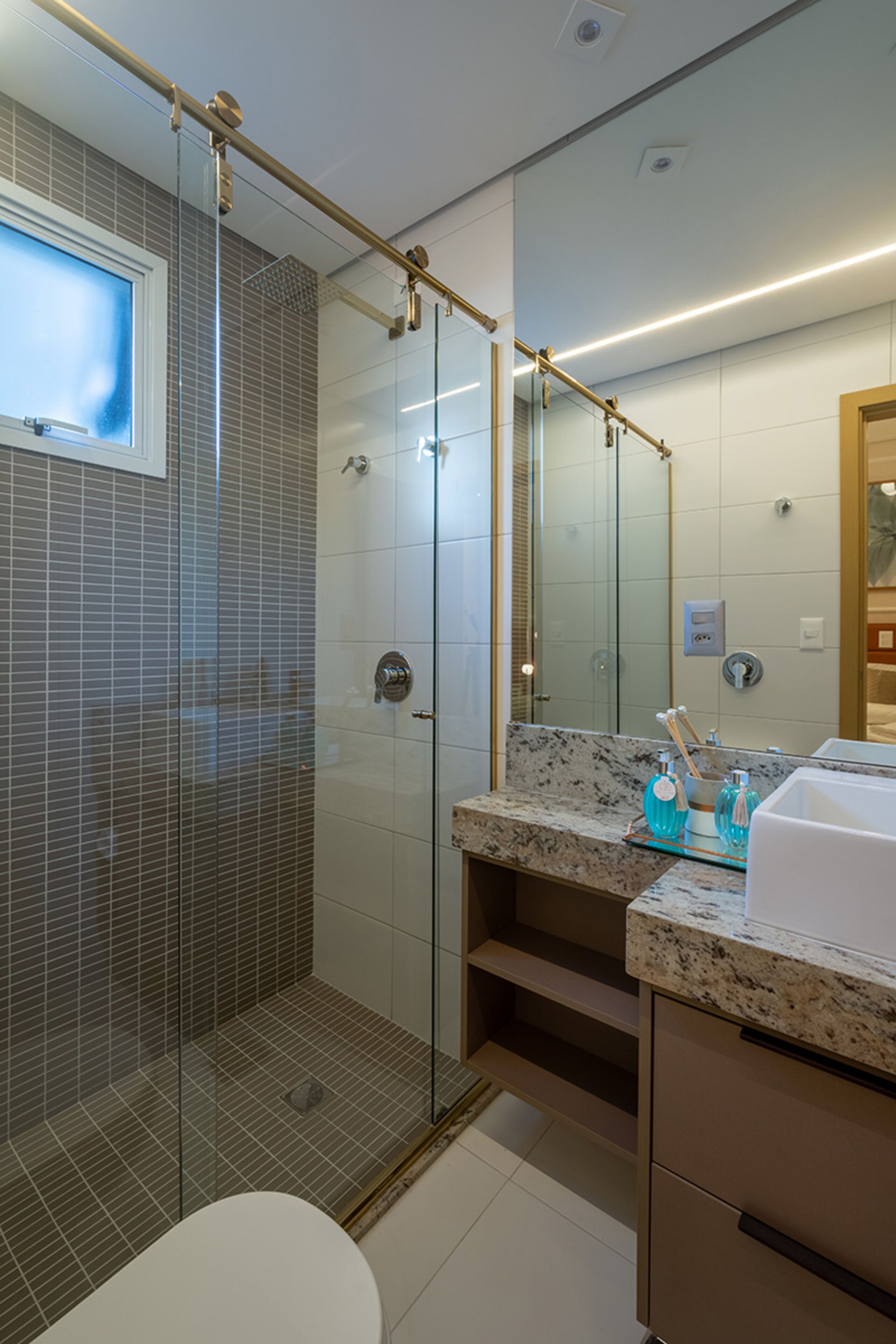 A modern bathroom with a glass-enclosed shower, a marble countertop, and a large mirror.
