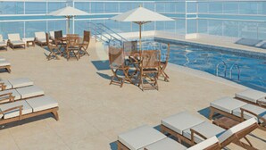 A rooftop pool area with lounge chairs and umbrellas. - Santos Linda !! 5 min from the beach ! (SP)