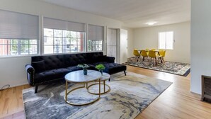 A living room with a black sofa, a round coffee table, and yellow chairs.
