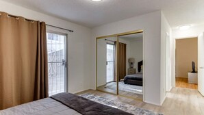 A bedroom with a bed, a large mirror, and a sliding door to a balcony.