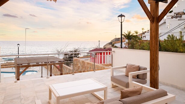 A terrace with a pool, outdoor seating, and a view of the sea.