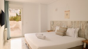 A hotel room with a bed, a wooden headboard, a small table, and a TV on the wall.