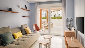 A modern living room with a grey sofa, a red chair, and a small wooden table.