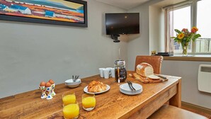 Une table de petit-déjeuner avec des œufs, des croissants, du pain, du jus de fruits et une machine à café.