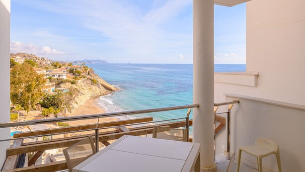A balcony with a view of the sea and a hillside town.