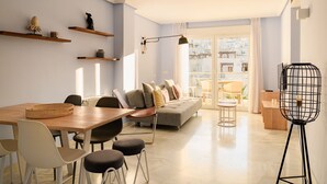 A modern living room with a sofa, dining table, chairs, and a floor lamp.