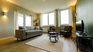 A modern living room with a sofa, armchairs, a coffee table, and a TV.