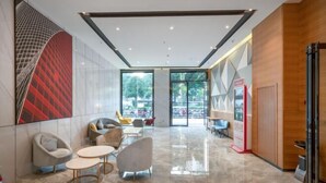 A modern lobby with a glass wall, seating area, and a reception desk.