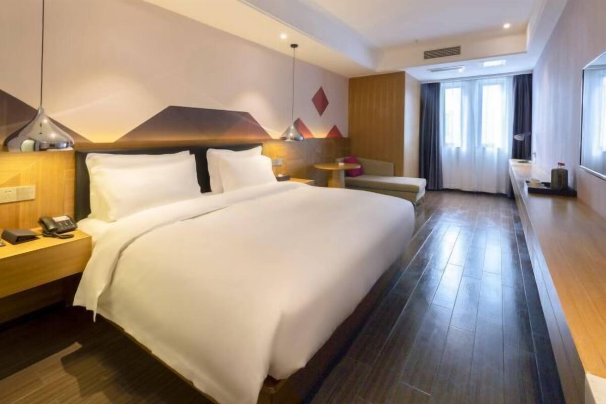 A hotel room with a large bed, bedside tables, a desk, and a chair.