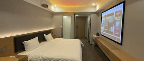 Una habitación de hotel moderna con una cama, una mesita de noche, una pantalla de televisión y un proyector en el techo.
