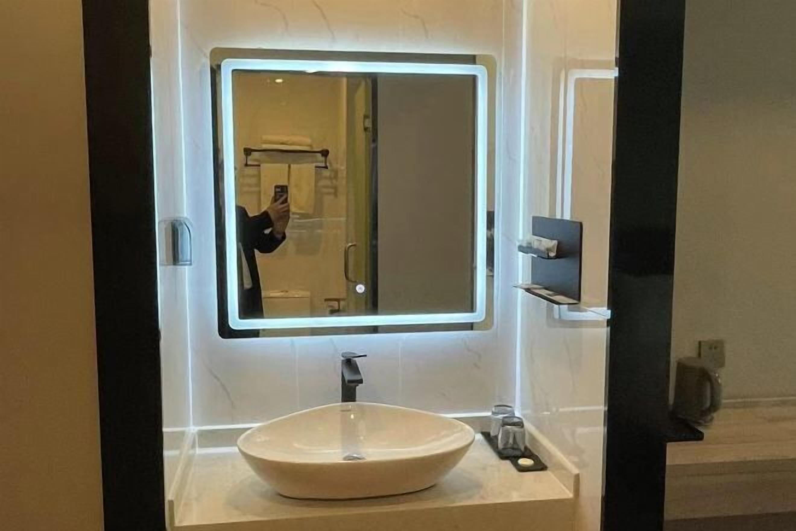 Ein modernes Badezimmer mit einem großen Spiegel, einem Händewaschbecken und einem Handspiegel.
