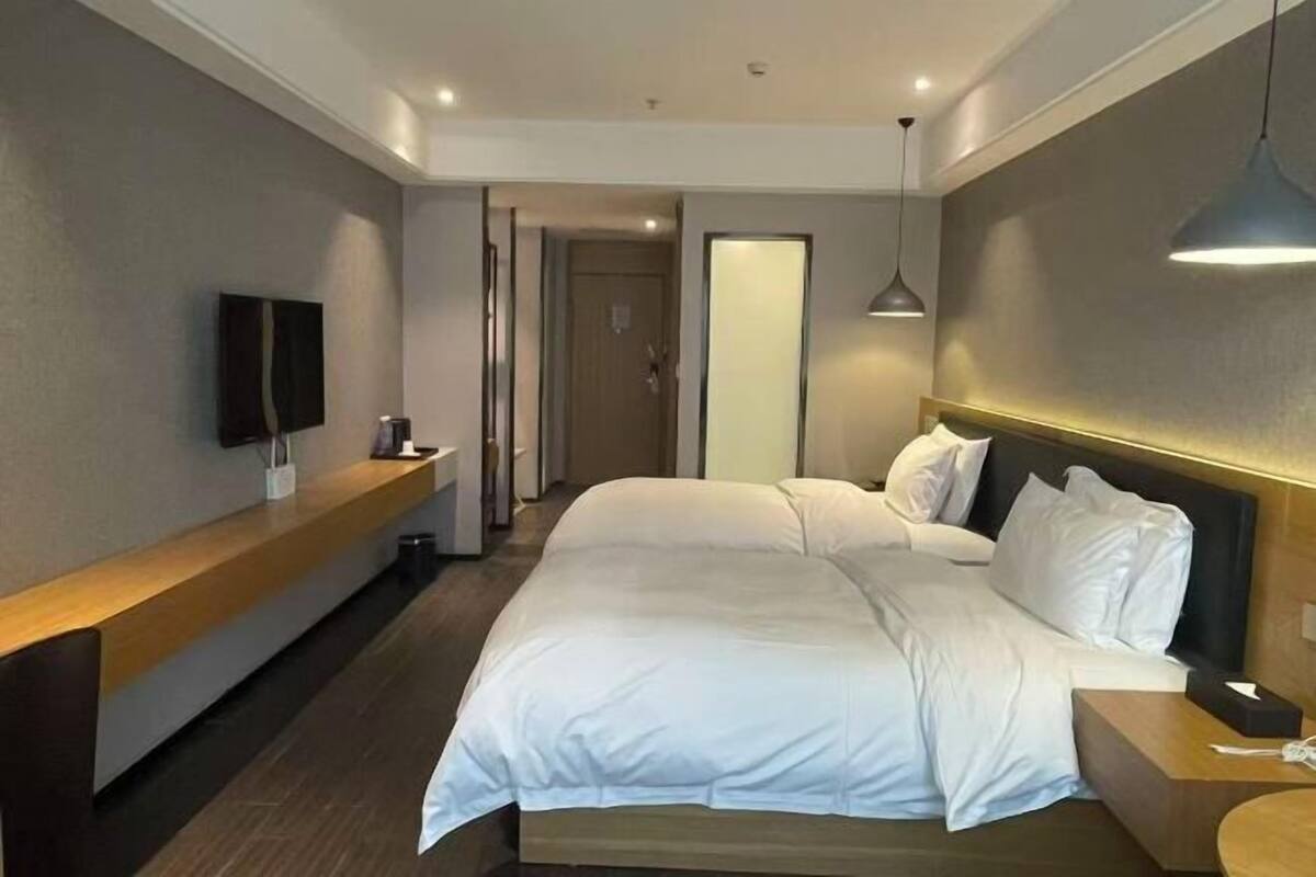 A modern hotel room with a large bed, bedside tables, a TV, and a mirror.