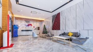 A modern lobby with a reception desk, a Christmas tree, a sofa, and a marble floor.