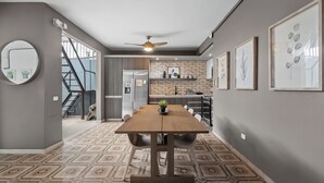 A modern kitchen with a central island, a dining area with a wooden table, and a staircase leading to an upper level. - La Buena Vida Inn (San Juan)