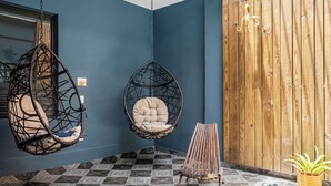 A room with two hanging chairs, a wooden bench, and a potted plant. - La Buena Vida Inn (San Juan)