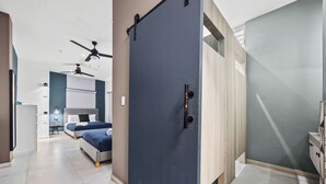A modern hotel room with a large sliding door, a bed, a desk, and a ceiling fan. - La Buena Vida Inn (San Juan)