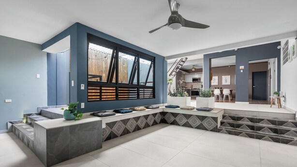 A modern kitchen with a large island, a built-in stove, and a window overlooking a wooden deck. - La Buena Vida Inn (San Juan)