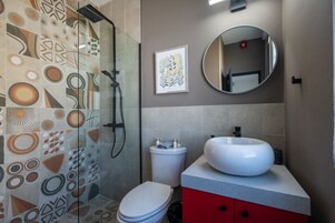 Un baño moderno con baldosas estampadas, inodoro blanco, un lavamanos grande y una ducha.