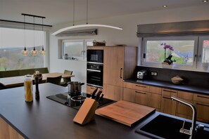 A modern kitchen with a large island, built-in oven, and a window with a view of the outdoors.