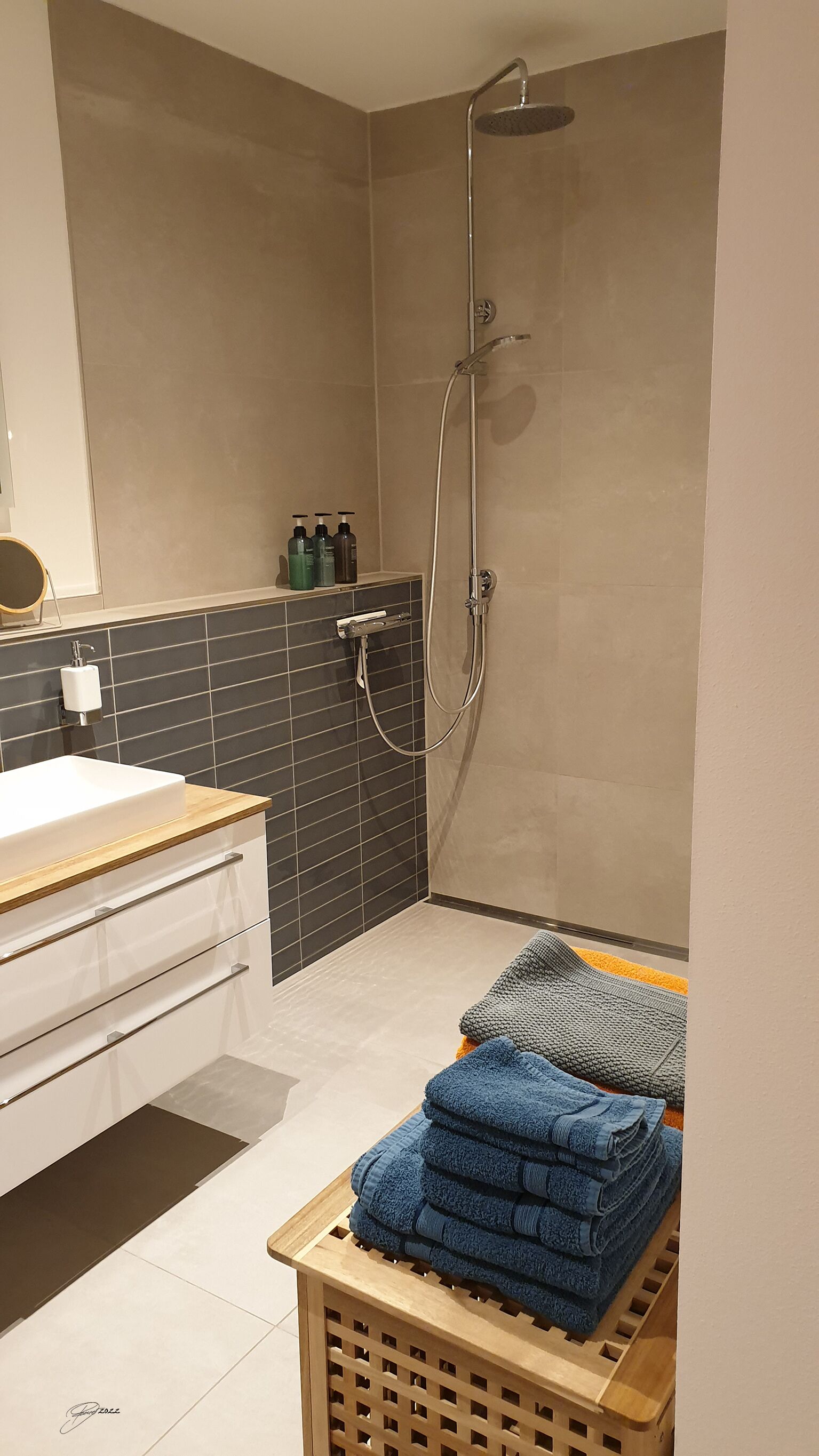 A modern bathroom with a shower, a sink, and a towel rack.