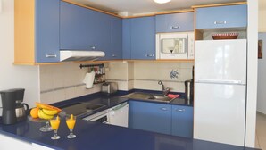 A compact kitchen with blue cabinets, a white refrigerator, a microwave, a toaster, and a coffee maker. - House Maresía Las Moreras Duplex with Sea View 1 minute from the seafront promenade  (Playa Blanca)