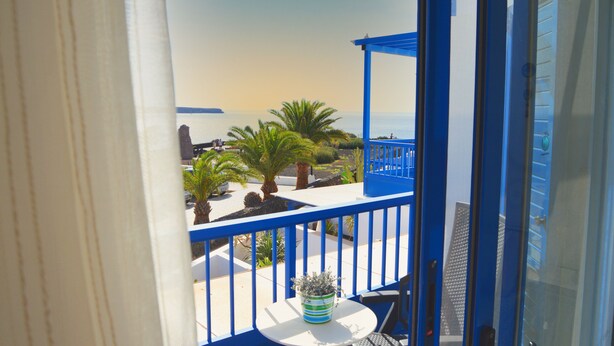 A balcony with a view of the sea, palm trees, and a blue railing. - House Maresía Las Moreras Duplex with Sea View 1 minute from the seafront promenade  (Playa Blanca)