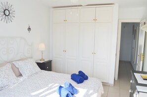 A bedroom with a bed, a nightstand, a wardrobe, and a desk with a lamp. - House Maresía Las Moreras Duplex with Sea View 1 minute from the seafront promenade (Playa Blanca)