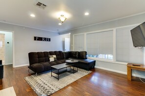 Uma sala de estar moderna com um sofá seccional, uma mesa de centro e uma televisão.