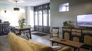 En moderne stue med sofa, spisebord og fjernsyn.