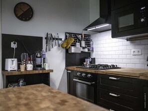 Una cocina moderna con microondas, estufa, horno y varios utensilios en la pared.