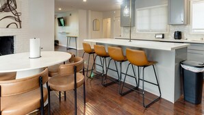 Una cocina moderna con una isla central, taburetes de bar y una chimenea.