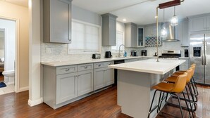 Una cocina moderna con armarios grises, una isla blanca y un refrigerador de acero inoxidable.