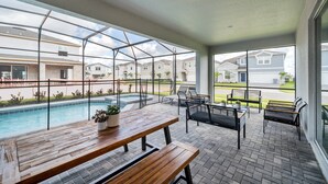 A covered patio area with a pool, outdoor seating, and large windows offering views of neighboring houses. - Star Wars Themed Game Room • Private Pool • Lazy River • Resort • Near Disney (Davenport)