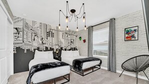 A modern bedroom with two beds, a black metal chair, a mural on the wall, and a ceiling light fixture. - Star Wars Themed Game Room • Private Pool • Lazy River • Resort • Near Disney (Davenport)
