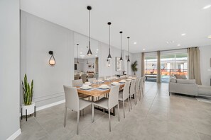 A modern dining area with a long table set for a meal, surrounded by chairs.