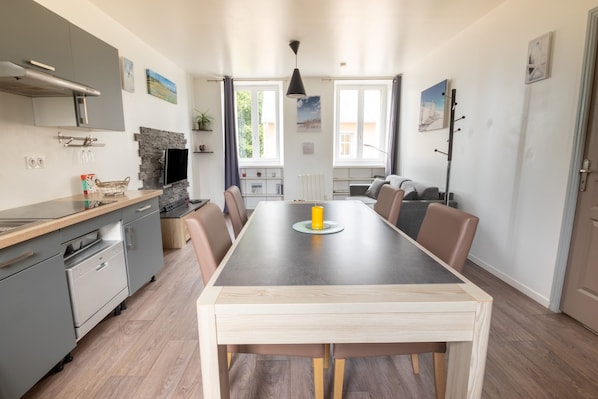 A modern kitchen with grey cabinets, a built-in oven, and a dining area with a wooden table and chairs.