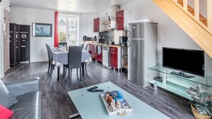 A modern apartment with a dining area, kitchen, living room, and a staircase.