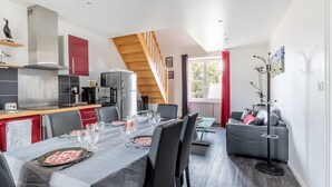 A modern kitchen with a dining area, a staircase, and a living room with a sofa.