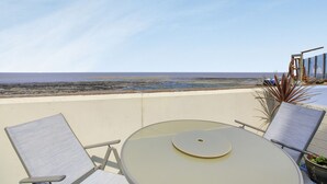 A balcony with two chairs and a table, overlooking a beach. - Sea Spray (Watchet)