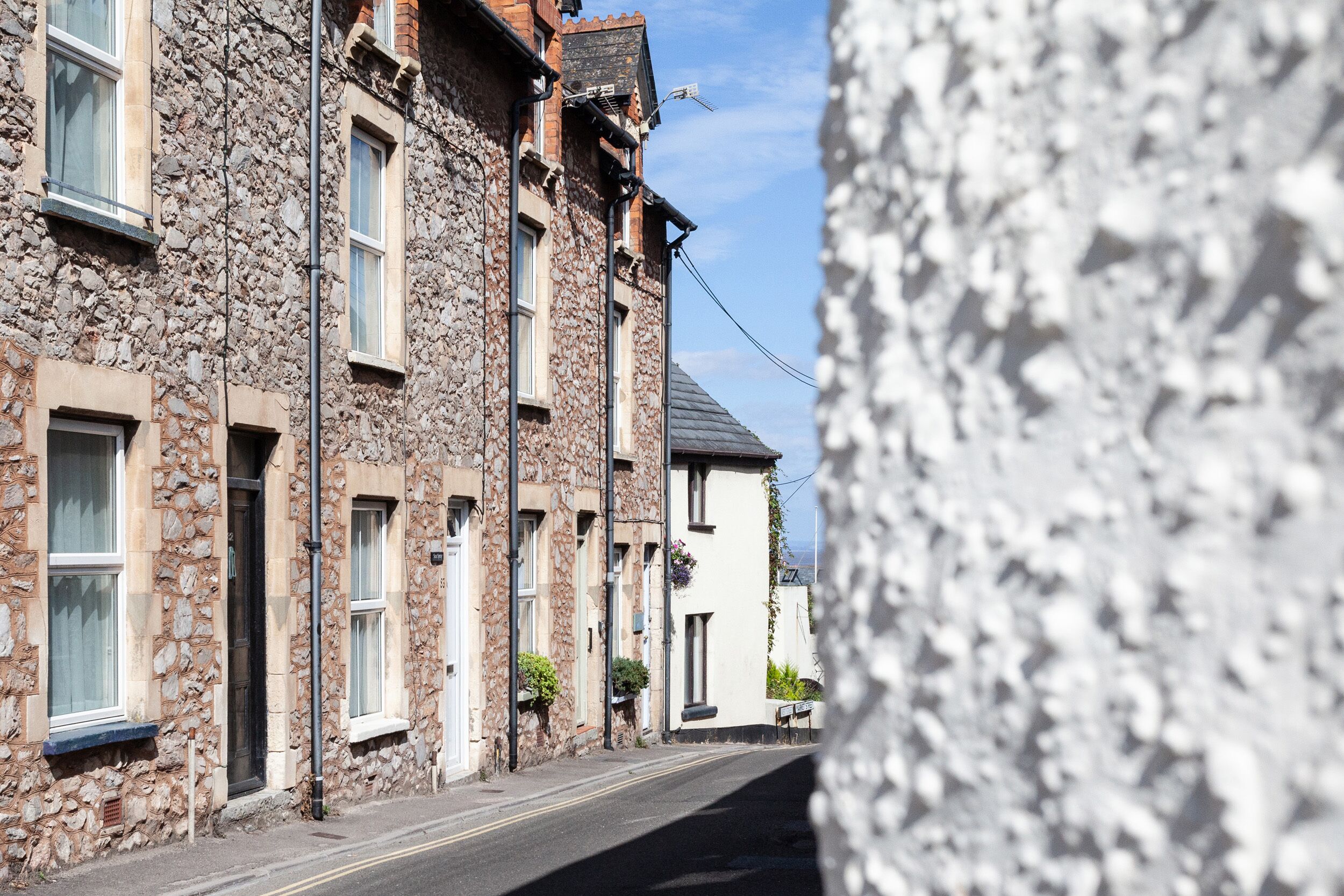 Une rue étroite bordée de bâtiments en pierre, avec de nombreuses fenêtres et un ciel dégagé.