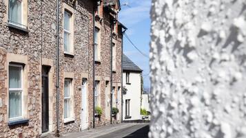 Une rue étroite bordée de bâtiments en pierre, avec de nombreuses fenêtres et un ciel dégagé.