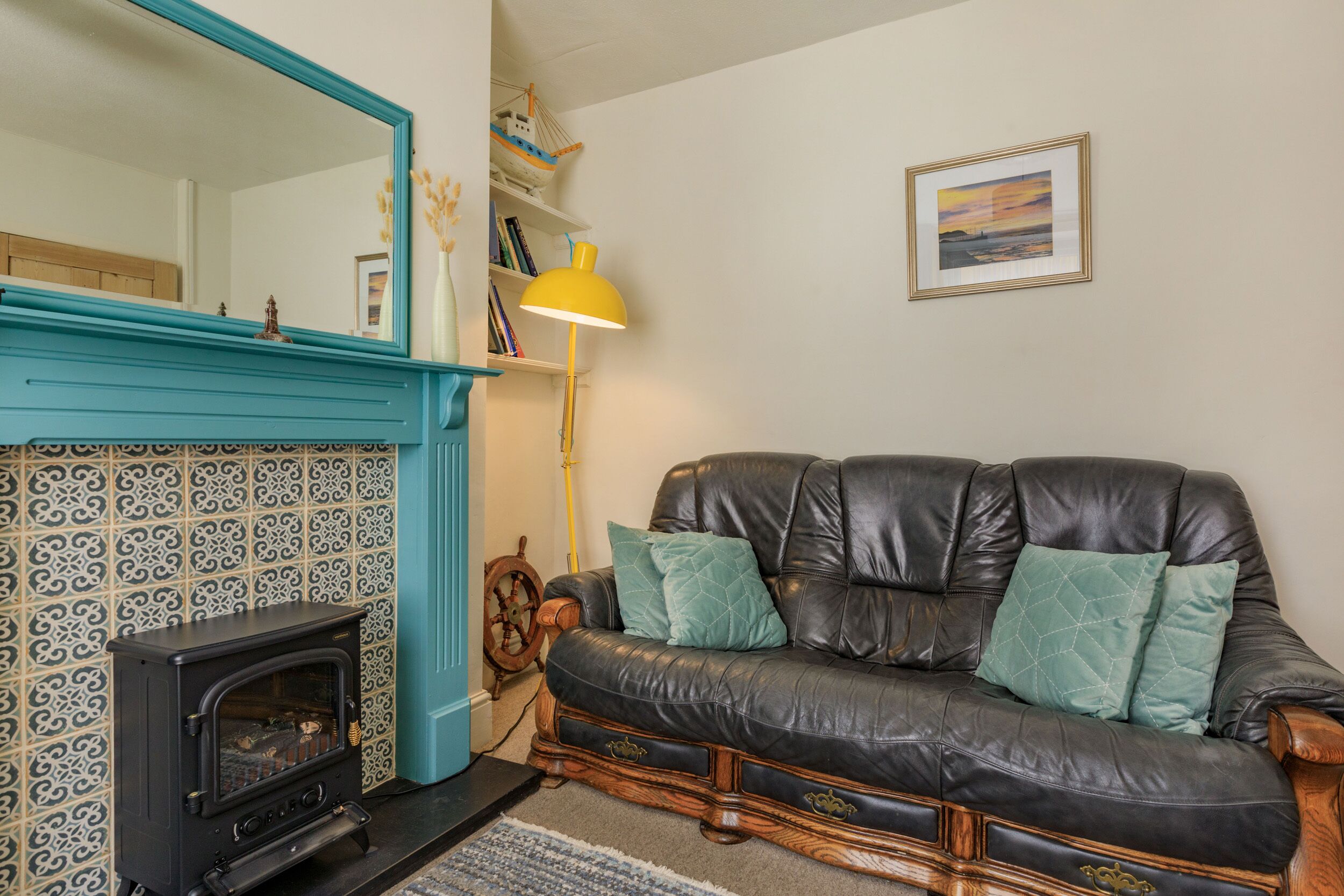A cozy living room with a fireplace, a leather sofa, and a large mirror.